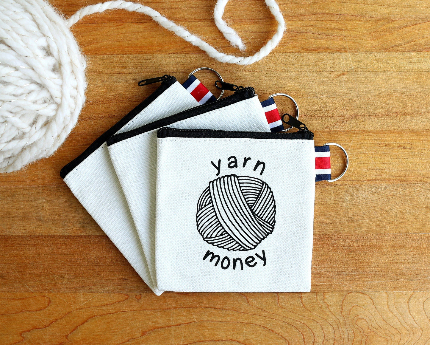 Canvas zipper pouch with yarn ball illustration and 'yarn money' text, ideal for crafters.