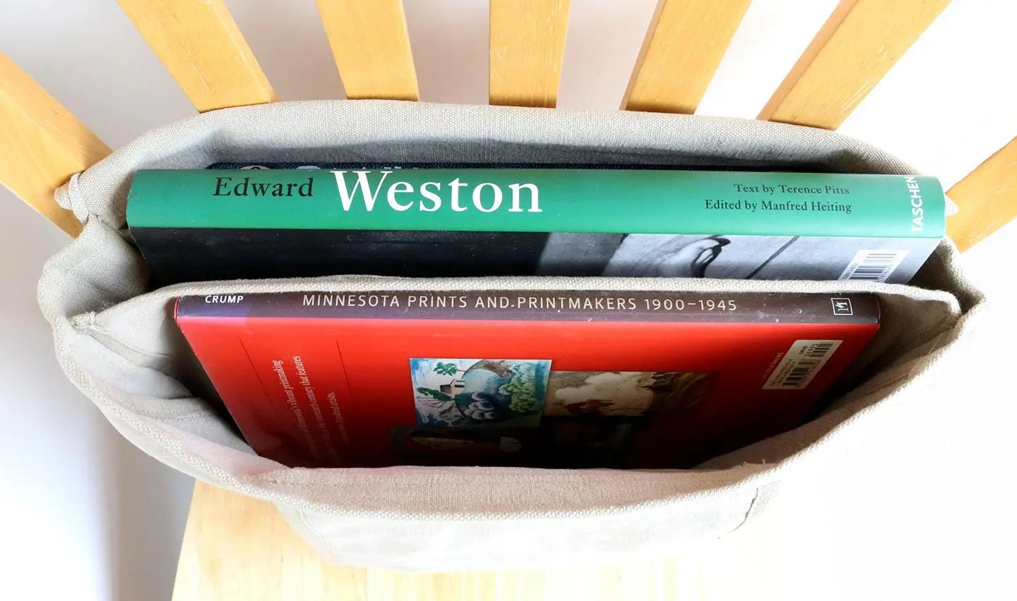 Neutral canvas book bag holding two art books on a wooden chair